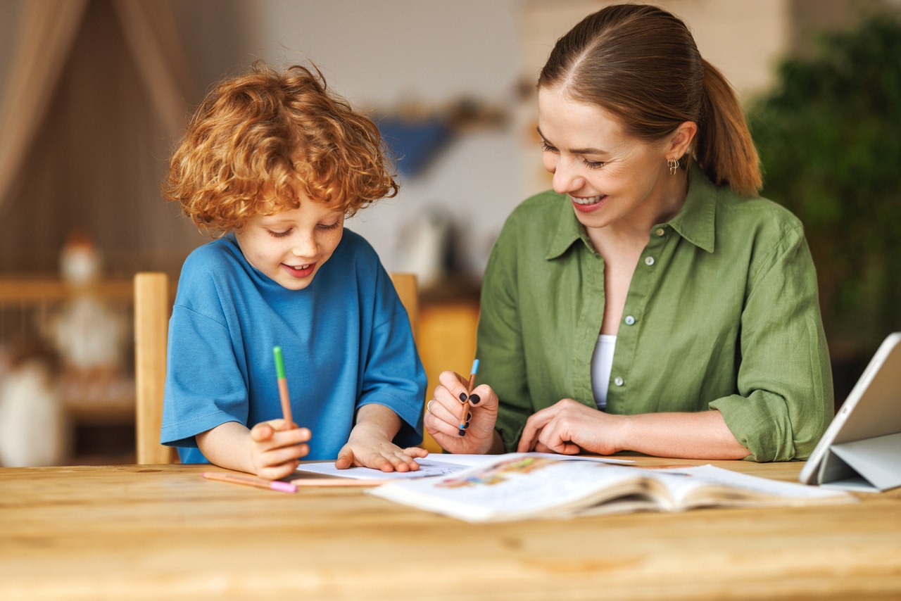 cheerful mother doing homework with son at home