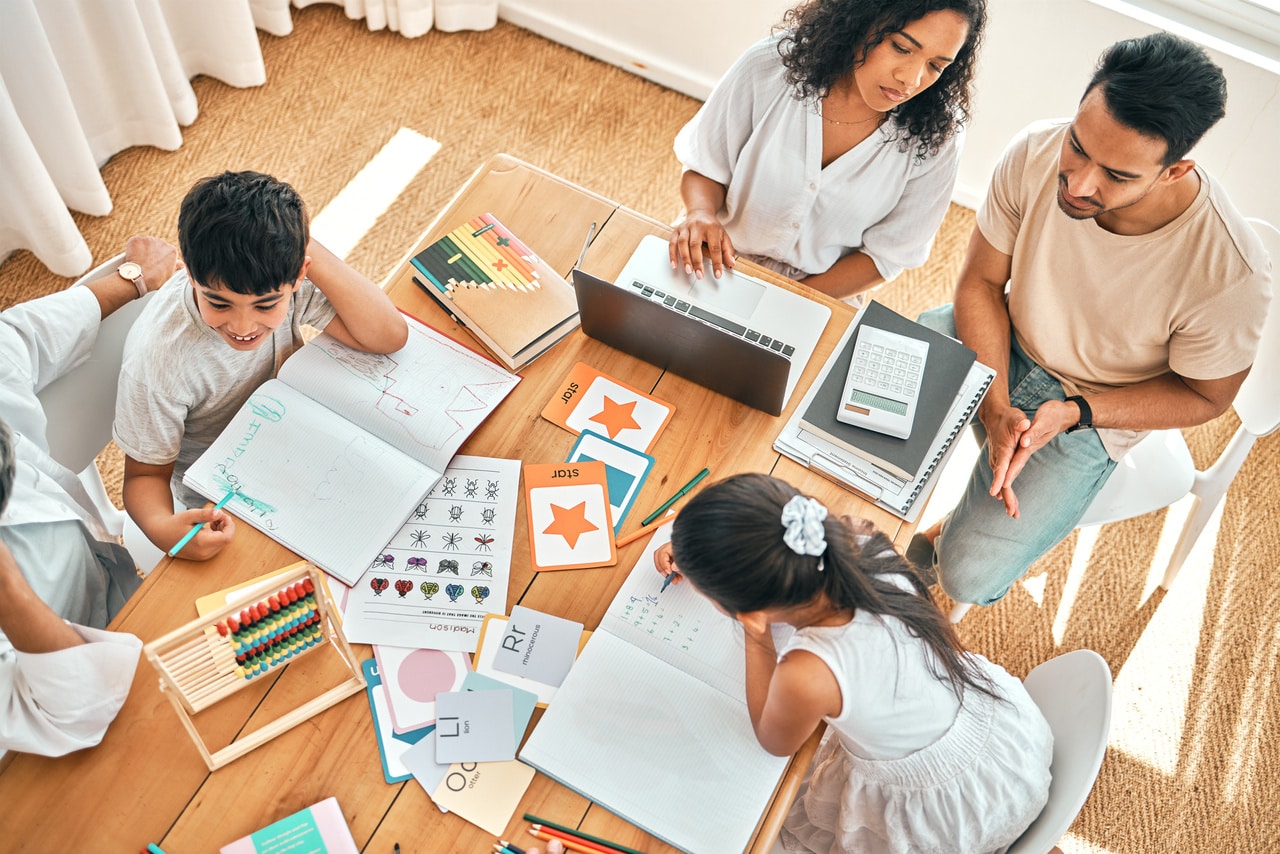 education, learning and family together with homework, academic material and children study, people and table top view. parents helping kids, learn and mother with laptop, growth and development