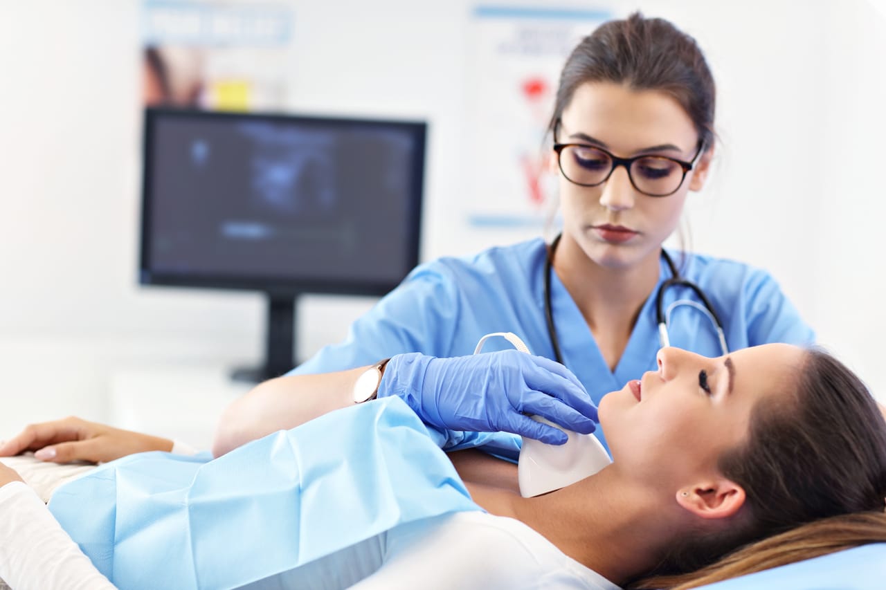 adult woman having thyroind ultrasound test at female doctor's office