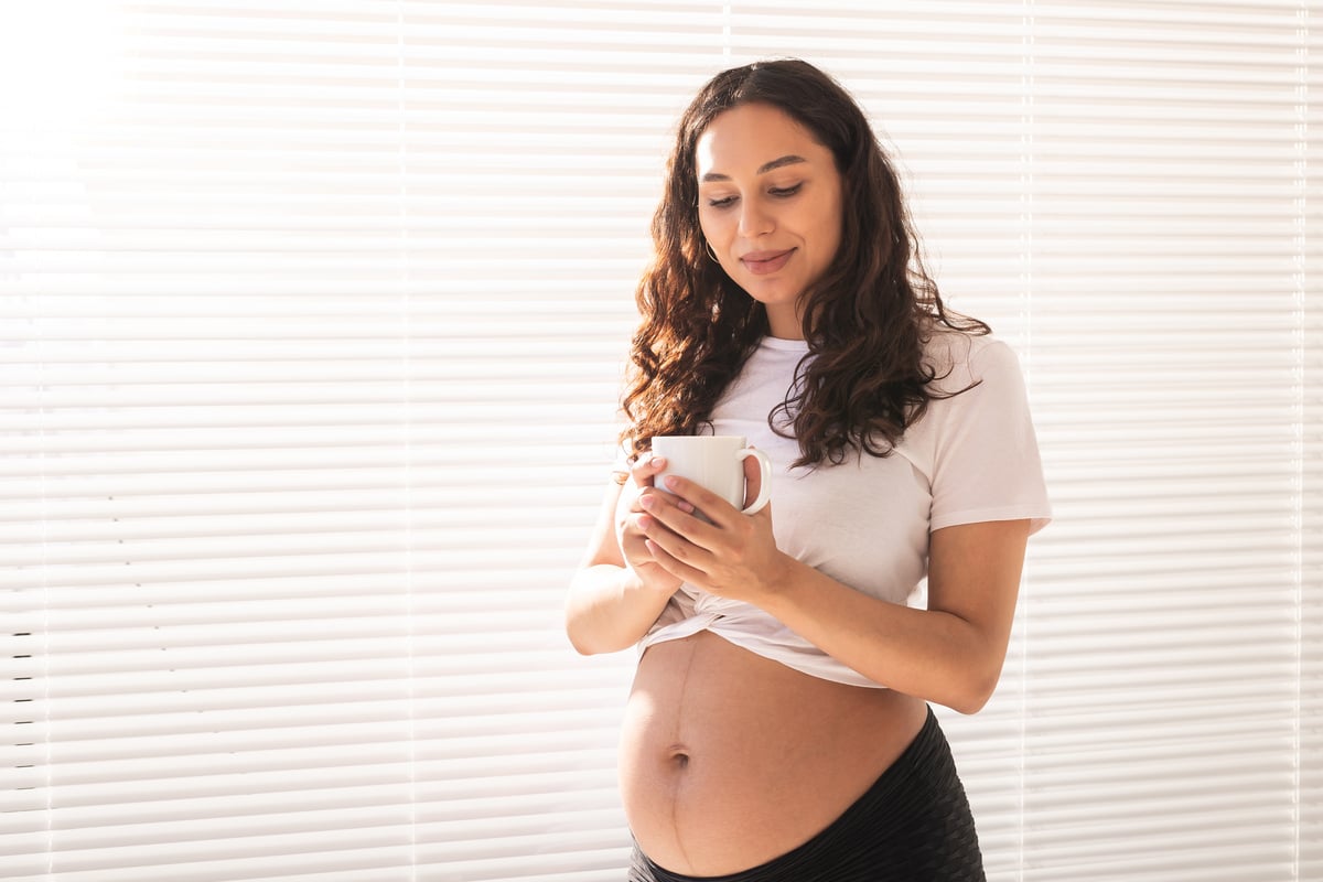 happy pregnant young beautiful woman drinks tea during morning breakfast. pregnancy and maternity leave. copy space.