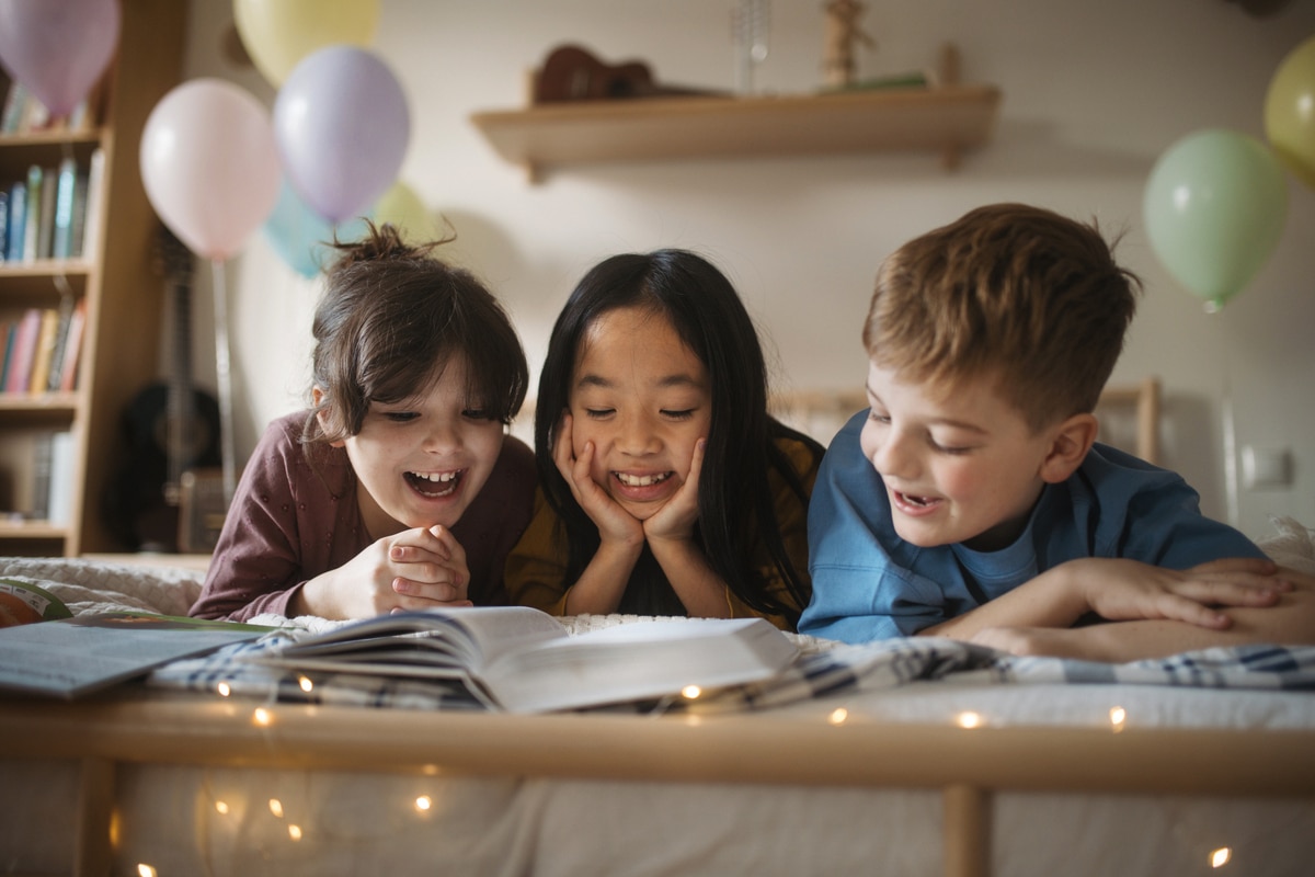 three happy friends reading a book together in a room.