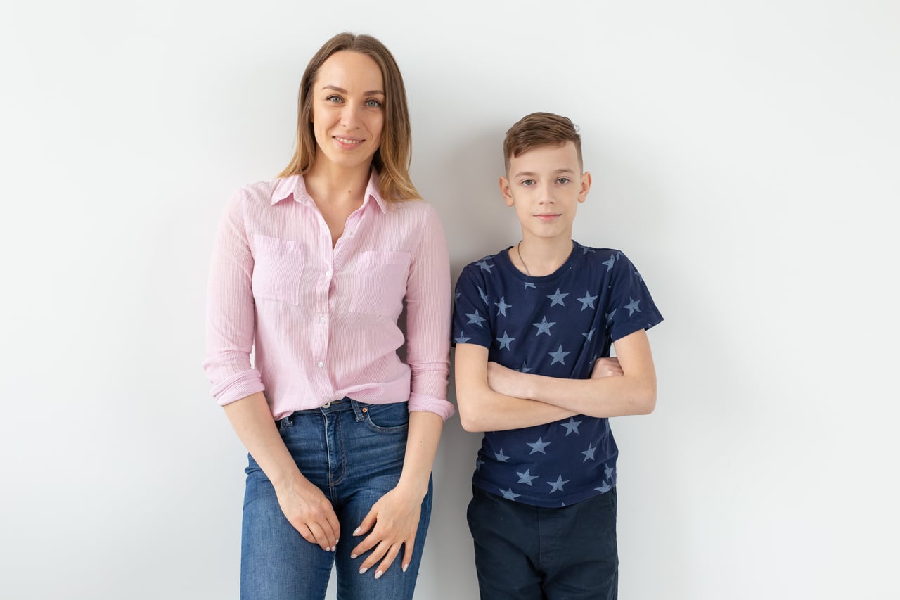 good looking single parent mom and teen son on white background. cohesion, friendship and family relations.