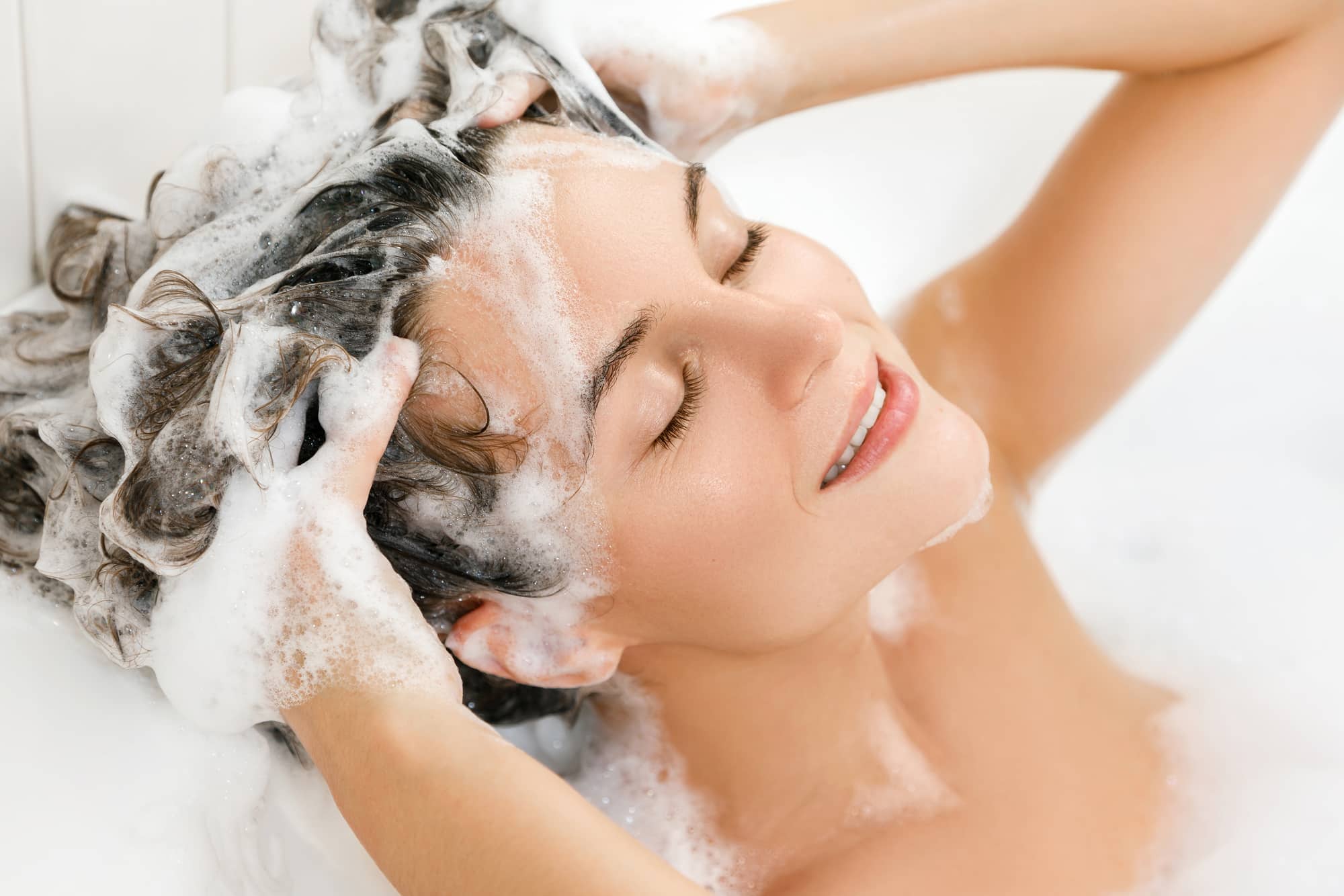 woman is washing her hair with shampoo