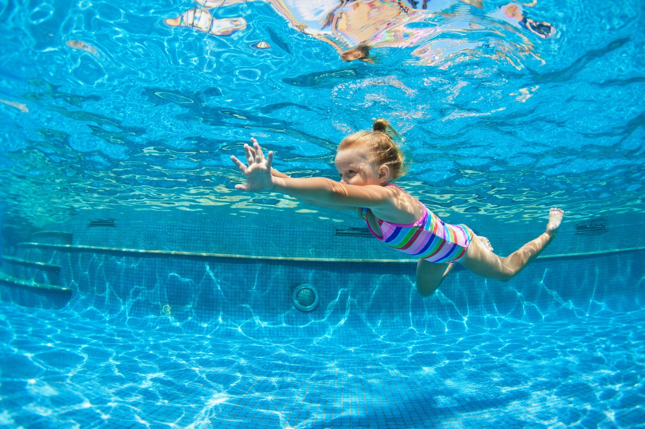 child jump underwater into swimming pool