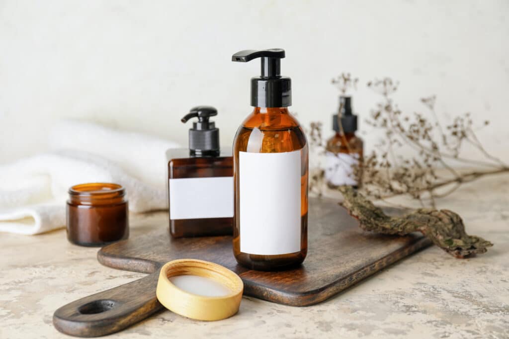 bottles with natural shampoo on light background