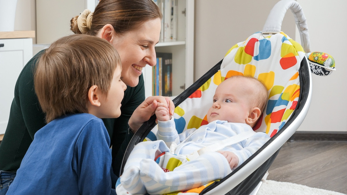 happy baby boy rocking in chair next to his family sitting in living room. child development and happy childhood