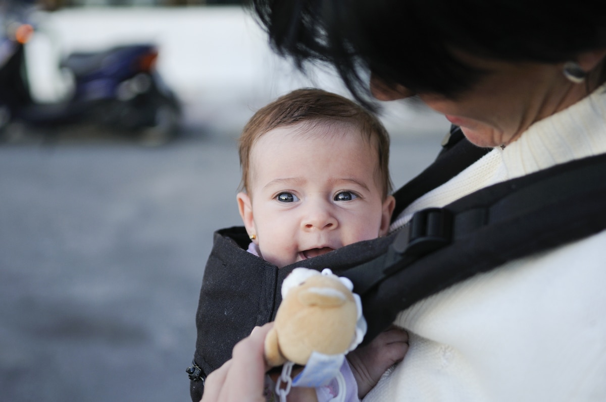 mother carrying her baby girl in a baby carrier