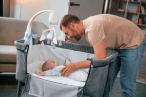 newborn baby is in the cradle. father is indoors. conception of single dad