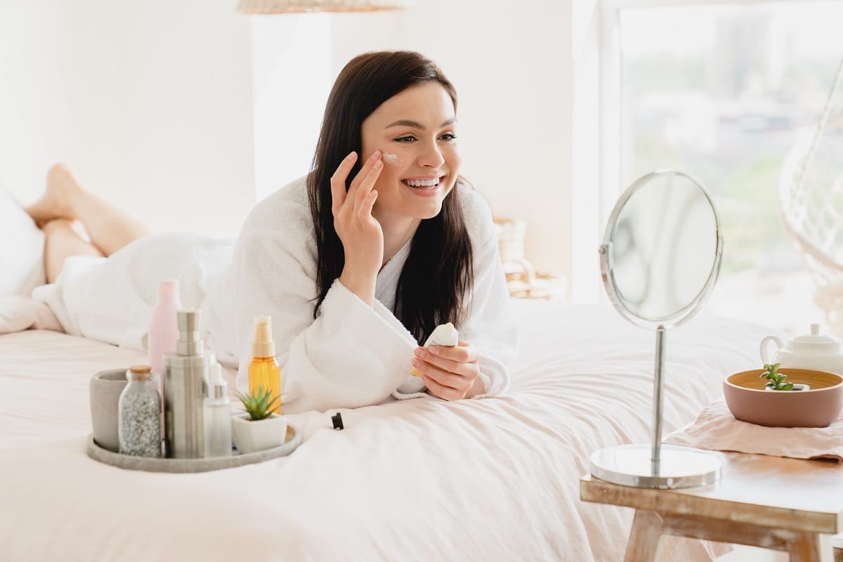 young caucasian girl woman using softening moisturizing face cream for skin face care.