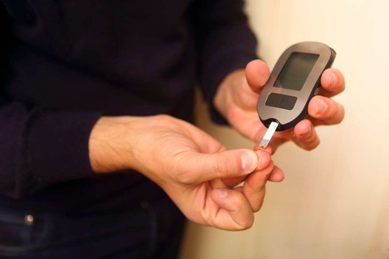 man inserting blood test strip in glucometer for m 2022 11 11 21 53 56 utc