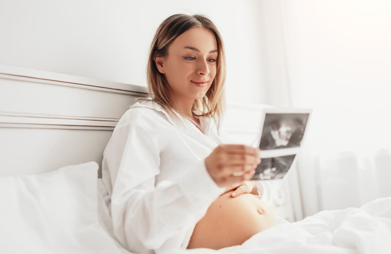 pregnant woman examining sonogram scan on bed 2022 11 23 00 42 23 utc