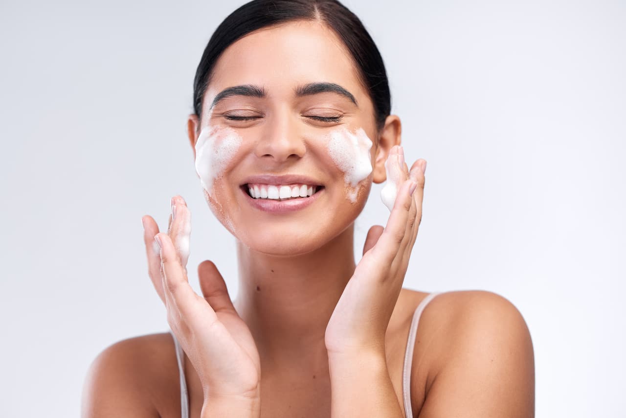 studio shot of a beautiful young woman washing her face.