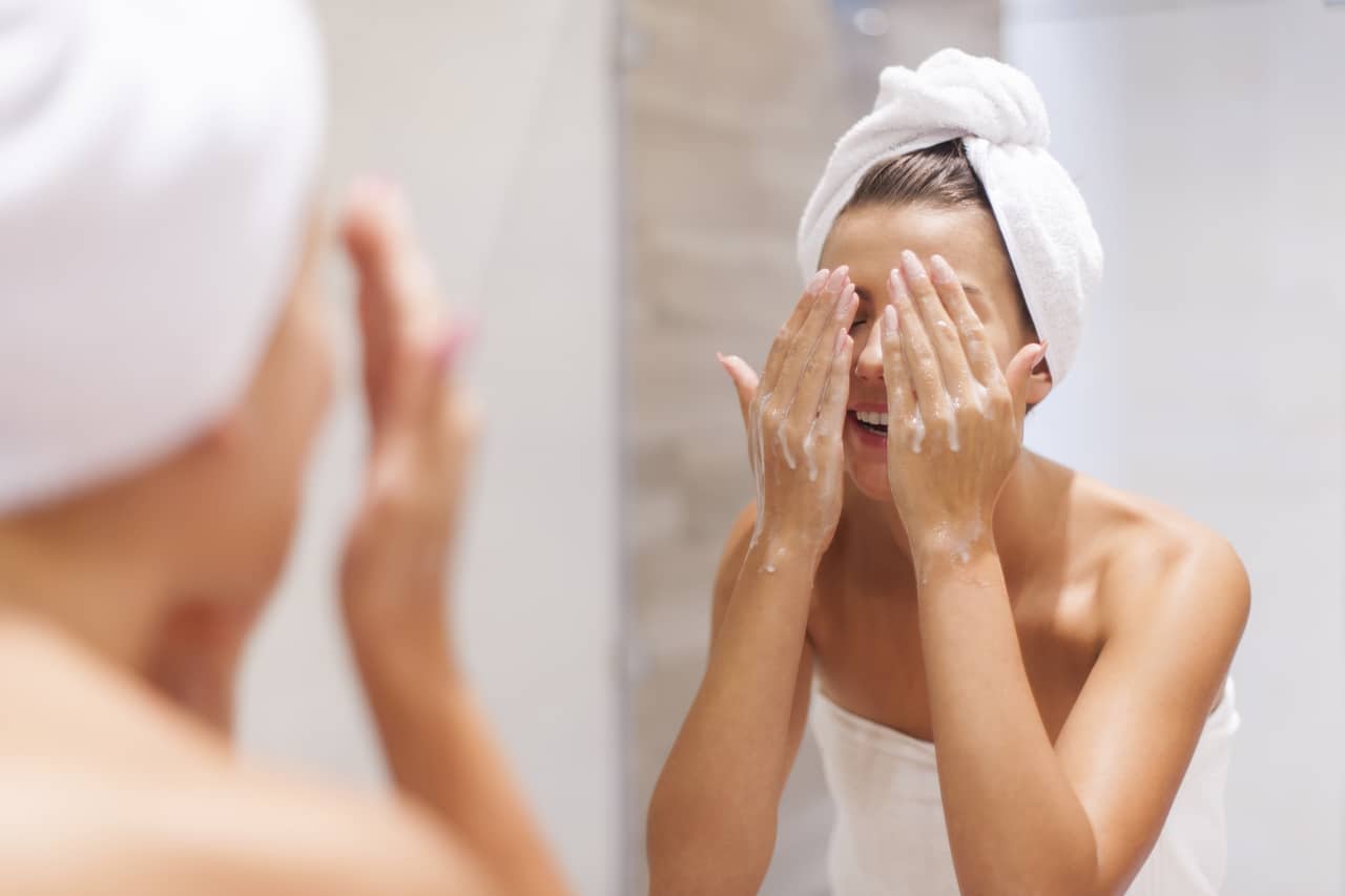 woman washing face in bathroom