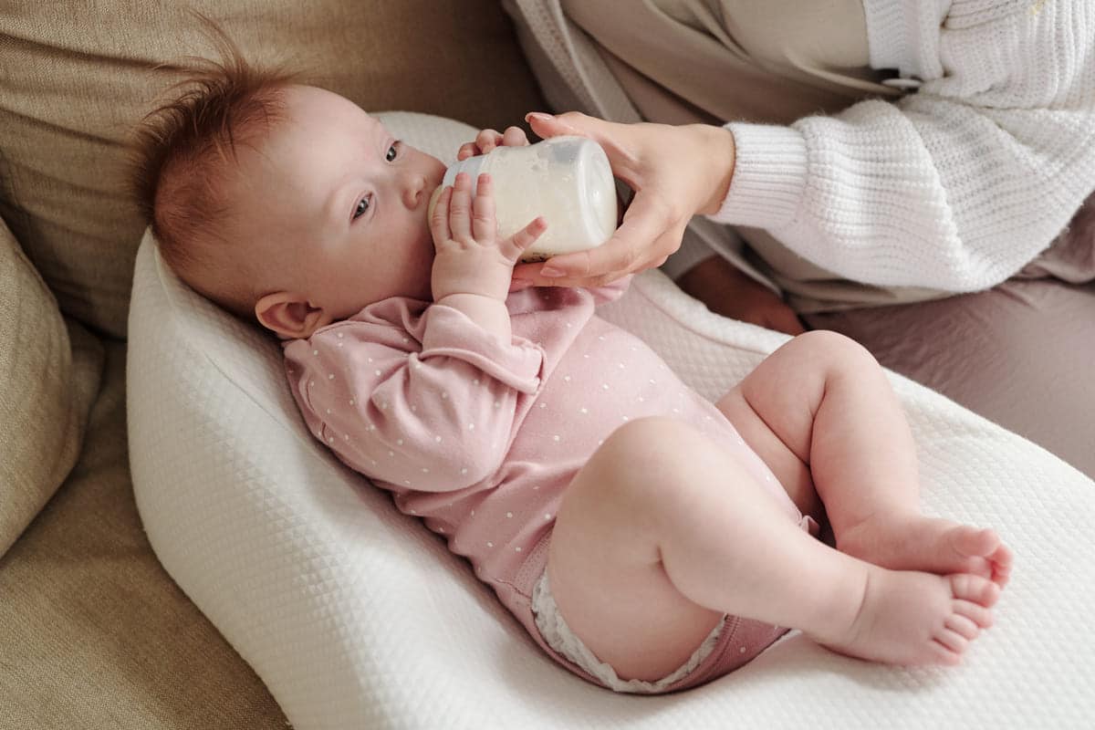 cute baby eating milk from bottle held by mom 2021 09 24 02 49 25 utc(1)(1)