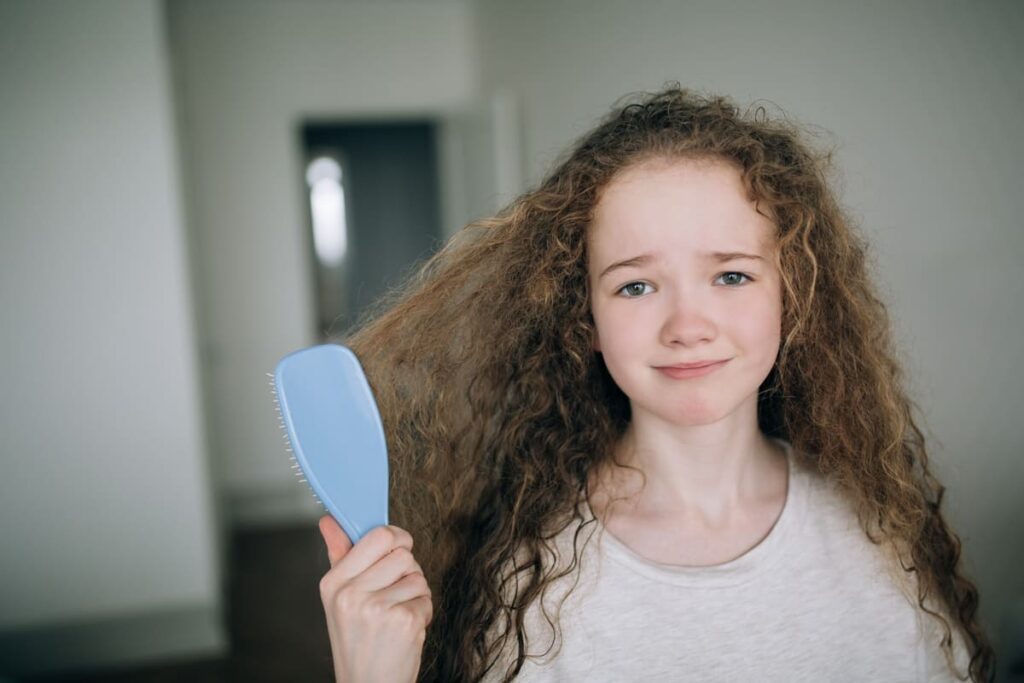 a girl combing her tangled curly hair in her bedro 2022 11 10 08 26 37 utc(1)(1)