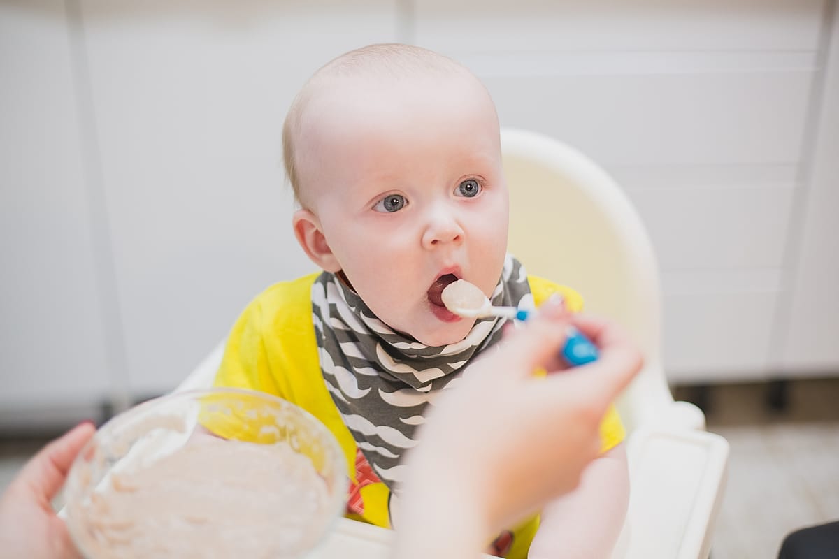 mom feeds the baby from a spoon caring for the ba 2022 11 15 05 36 54 utc(1)