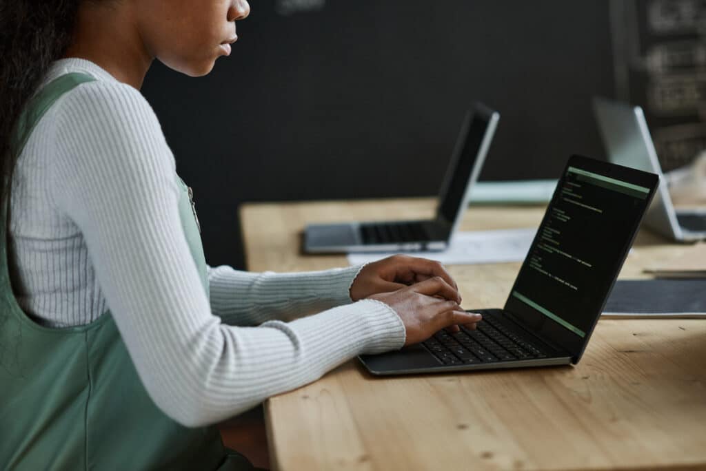 schoolgirl typing codes on laptop at class