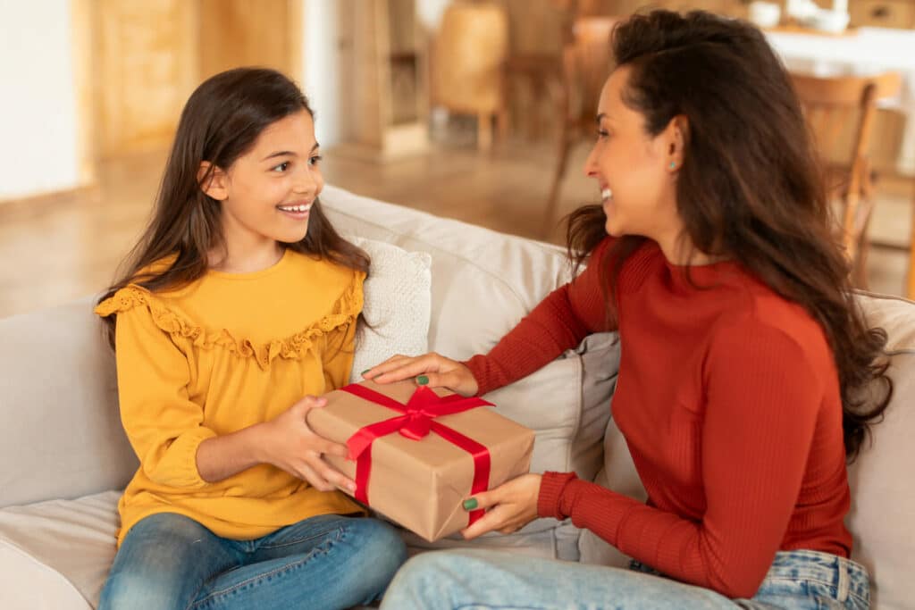 smiling kid girl giving birthday gift to mom at ho 2023 10 05 04 49 26 utc(1)(1)