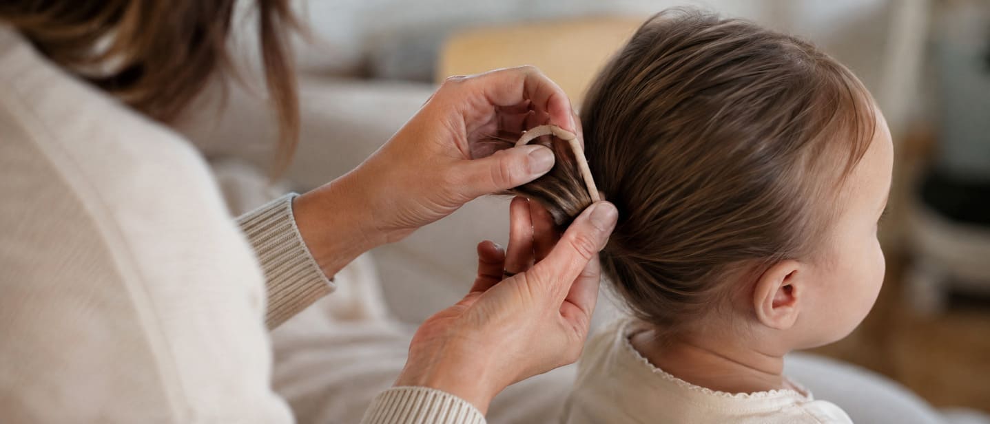 Adult carefully unwinding a hair elastic from a baby's hair