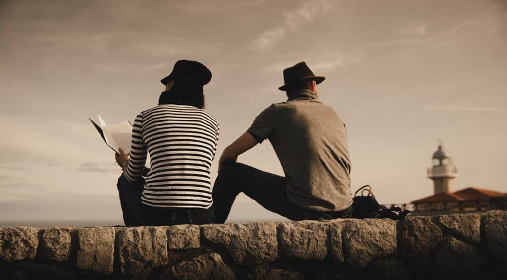 man and woman on stones near lighthouse